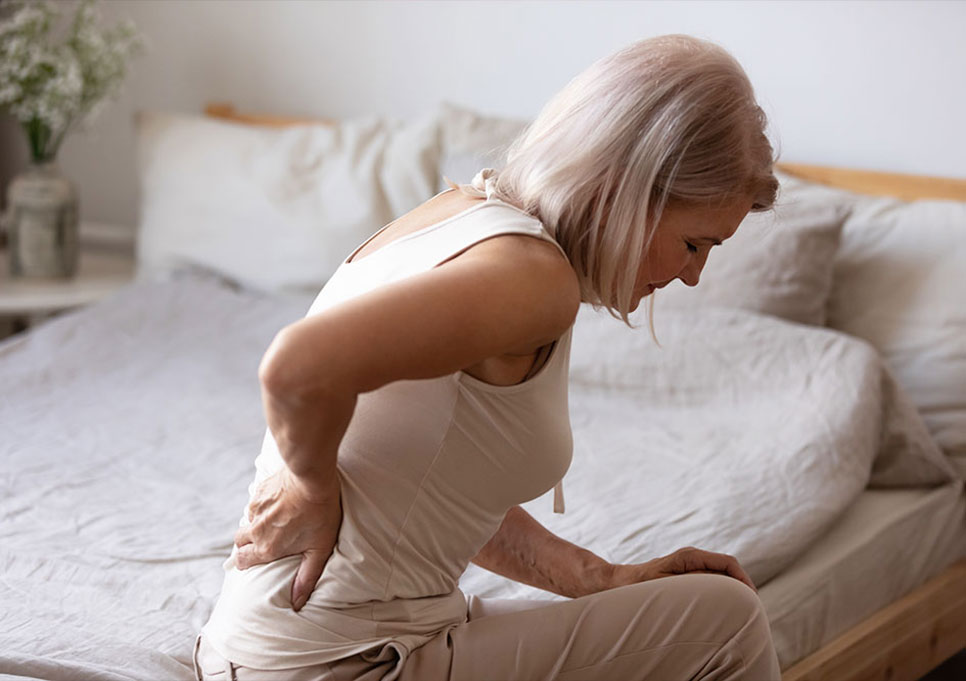 Woman sitting on her bed in pain from lumbar injury