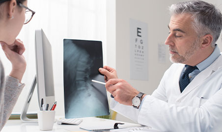 Doctor exams spine for severity of spinal stenosis